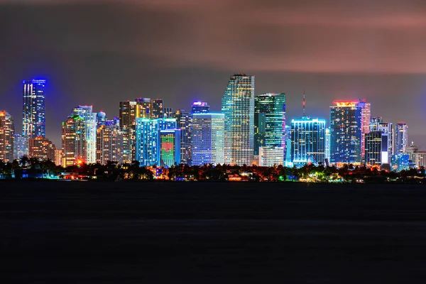 Skyline città miami illuminazione luci mare oceano tramonto notte paesaggi urbani edifici centro, architettura grattacielo crepuscolo panorama. Miami notte in centro. — Foto Stock