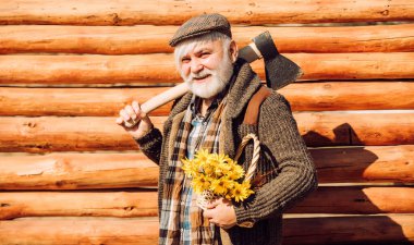 Ahşap arka plan. Çiçekli yaşlı hippi. Sakallı ve bıyıklı mutlu adam çiçek sepeti tutuyor. Baltalı yaşlı sakallı adam. Sakallı yaşlı adamın portresi.