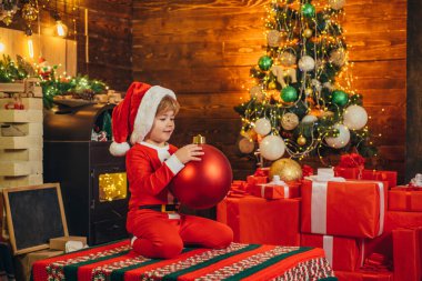 Mutlu çocuk Noel Baba kıyafetleri giyiyor, Noel ağacını süslüyor. Noel konsepti. Noel Baba yardımcıları.