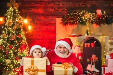 Hediyelerle dolu bir çanta taşıyan komik küçük Noel baba ve oğul. Noel Baba çocuk büyükbaba ve torun. Çocuk Noel ağacının yanında gerçek Noel Baba 'yla oynuyor..
