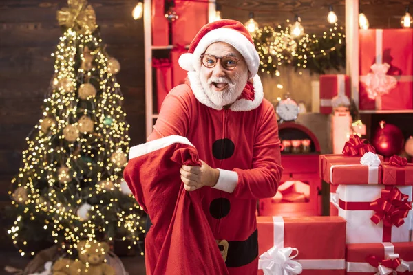 Portrait of handsome Santa man indoors with Christmas gift. New year concept. Santa old man posing on vintage wooden background. Men in winter clothes. — Stock Photo, Image