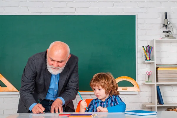 Pupil and Teacher in classroom. Senior teacher with pupil at back of classroom at the elementary school.