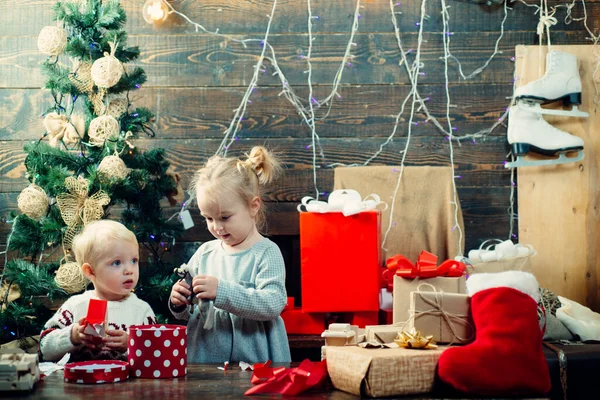 Glückliches Kind mit einem Weihnachtsgeschenk auf Holzuntergrund. Konzept Weihnachtsgeschichte. Niedliche kleine Kinder feiern Weihnachten. Weihnachtskinder - Glückskonzept. kiddy. — Stockfoto