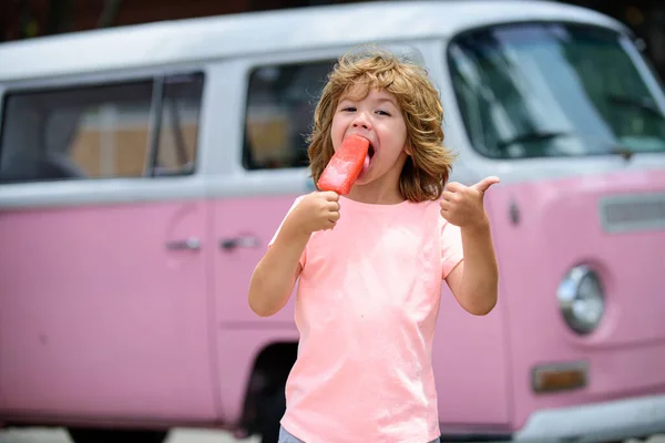Bambino con dolce congelato in mano. Ragazzo vestito di rosa che mangia un gelato. — Foto Stock