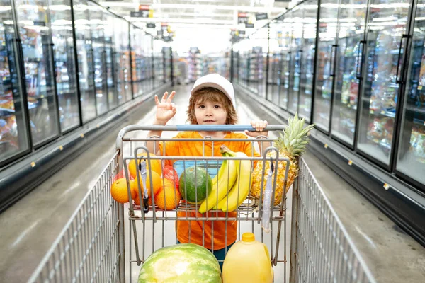 Bambino con la borsa della spesa al supermercato. Shopping per bambini in un supermercato. Bambino carino con carrello della spesa con prodotti. — Foto Stock