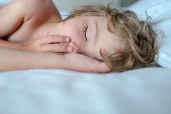 Små barn som ligger med munnen öppen, snarkar. Grabben i sovrummet sover på sängen med vitt lakan och kudde. — Stockfoto