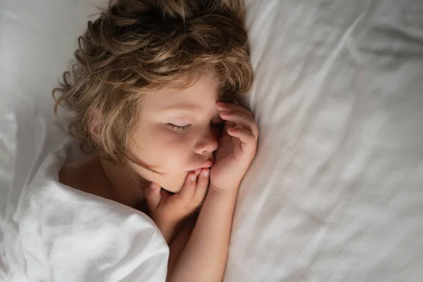 Miúdos giros dormem na cama branca. Criança no quarto dormindo na cama com lençol branco e travesseiro . — Fotografia de Stock