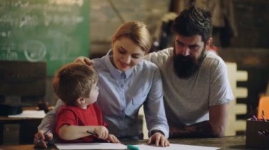 Öğretmenler ve öğrenciler sınıfta. Şirin küçük çocuk, anne ve babasıyla çalışıyor..