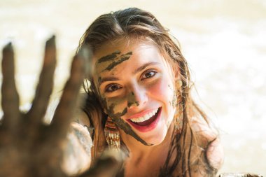 Kadın yüzü ve elleri çamurla kaplı. Çamur sağlıklı fırça..