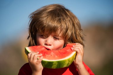Tatlı karpuz yiyen küçük sevimli çocuğun yakın plan portresi. Karpuz yiyen sevimli bir çocuğun portresi. Çocuk karpuz yiyor..