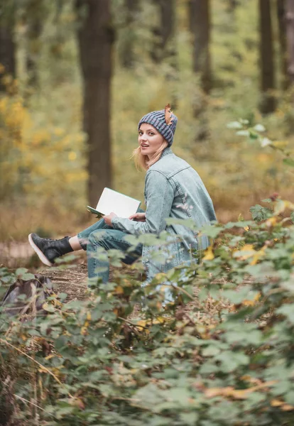 Kadınlar sonbahar doğa patikaları, ormanlar hakkında notlar yazar. Kadın yazar. Sonbahar havası. Dışarıda çimlerin üzerine kalem yazan bir kız. Ders çalışmak bir kitap okumak. Doğa Eğitimi Bir not yaz. — Stok fotoğraf
