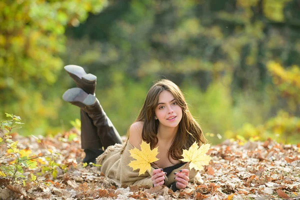 Uśmiechnięty portret szczęśliwej dziewczyny, leżący na jesiennych liściach. Na zewnątrz. Jesienny nastrój. Młoda kobieta ciesząca się dobrą pogodą. — Zdjęcie stockowe