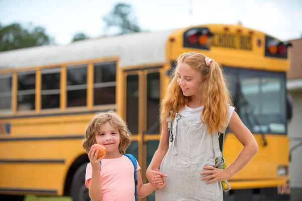 Zurück zur Schule. Foto von zwei glücklichen Kindern, die aus den Fenstern eines gelben Schulbusses schauen. Viel Platz für Text. — Stockfoto