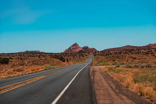 Ufukta asfalt yolu olan doğal Amerikan manzarası. Gün batımında çöl otoyolu, seyahat konsepti, ABD.
