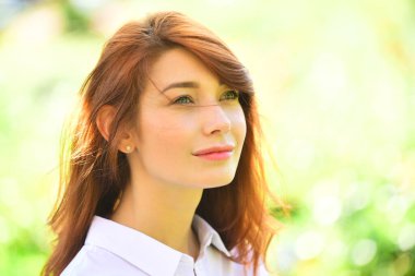 Çiçek açan arka planda duran kızıl saçlı güzel bir kızın yakın portresi. Yaz özgürlüğü kavramı.