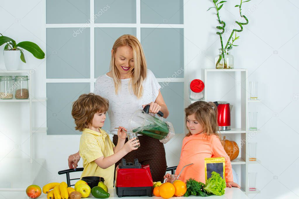 Mom daughter and son prepare a smoothie in the kitchen. Have fun and play with vegetables. Healthy diet and lifestyle for kids. Vegan nutrition and a healthy lifestyle. Happy loving family.