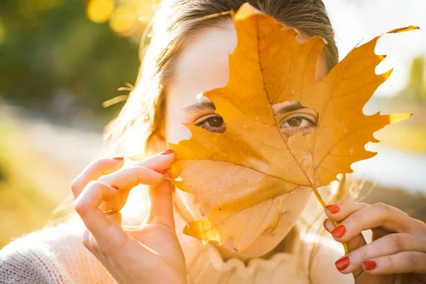 Podzimní žena se dívá ze žlutých listů. — Stock fotografie