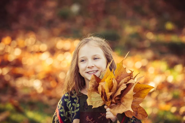 秋の都市公園で笑顔と楽しみを持っています。公園の中の愛らしい少女。暖かい晴れた秋の日に美しい秋の公園で遊んで幸せな女の子。愛らしい女の子の肖像画上の美しい秋の日. — ストック写真