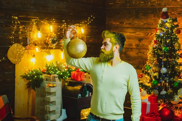 Γενειοφόρος άνθρωπος που διασκεδάζει κοντά σε χριστουγεννιάτικο δέντρο μέσα. Πορτρέτο του όμορφου Άη Βασίλη σε εσωτερικούς χώρους με στολίδι Χριστούγεννα. — Φωτογραφία Αρχείου