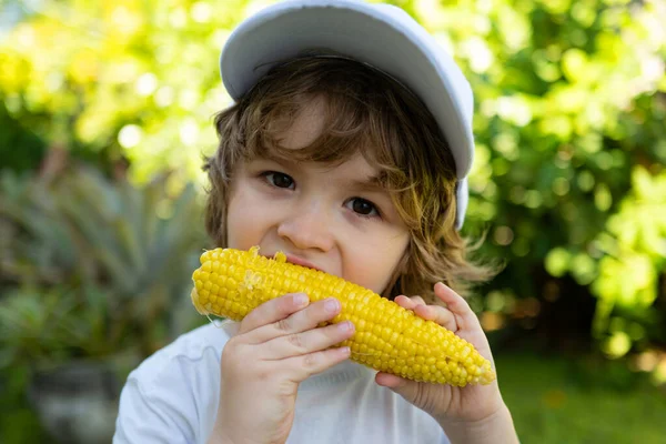 Um rapaz a comer milho na espiga. Comida para crianças . — Fotografia de Stock