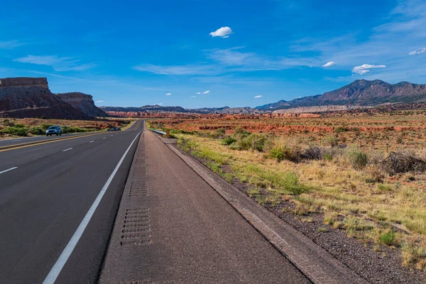 Klasický panoramatický pohled na nekonečnou rovnou cestu, která vede neúrodnou scenérií amerického jihozápadu. — Stock fotografie
