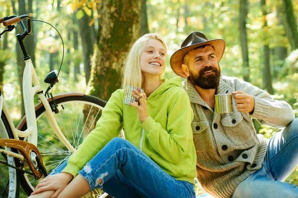 Les jeunes couples familiaux pique-niquent dans le parc automnal. Homme et femme assis sur une couverture de pique-nique et buvant du café chaud. Style de vie romantique. — Photo