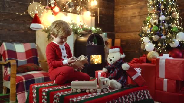 Dzieci z zabawkami świątecznymi. Dzień przed Nowym Rokiem. Szczęśliwe dziecko z darem. Wesoły słodkie dziecko otwierając prezent. — Wideo stockowe