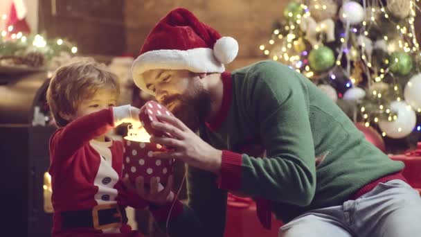Cute child son open Christmas gift from his father. Santa plays with kid. Father and son packing xmas gifts. Dad and son giving presents at home. — Stock Video