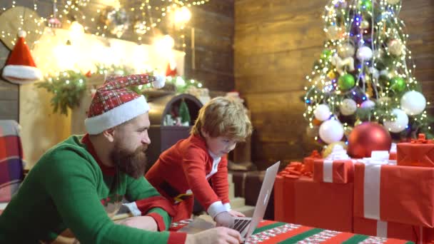 Otec a syn vypadající počítačové obrazovky a baví poblíž vánoční stromeček uvnitř. Otec a syn používají notebook ve vánočním domě. Rodinný koncept Happy People. — Stock video