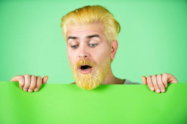 Elinde reklam panosu olan, yeşil stüdyo geçmişi olan bir adam..