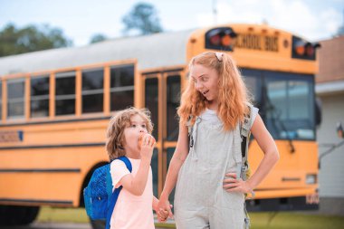 Okul otobüsü ve Mutlu Çocuklar. Okul otobüsünün önünde birlikte duran mutlu kız ve erkek kardeş portresi..