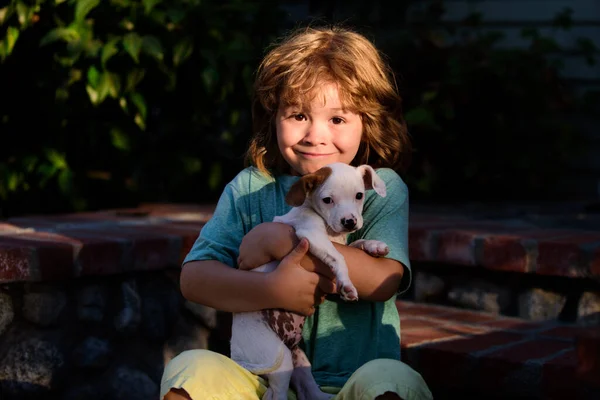 Puppy in the kids hands. Little boy hugging a dog. Happy kids and pet dog playing at backyard lawn. Kids with puppies. — Stock Photo, Image