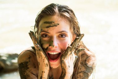 Kirli kadın model. Kil maskeli kadın gülüyor. Tıbbi çamura batmış deli bir kız. Kaplıcaya. Ölü denizdeki mutlu kirli kadın. Genç kadın, ölü denizden gelen doğal mineral çamurunun tadını çıkarıyor..