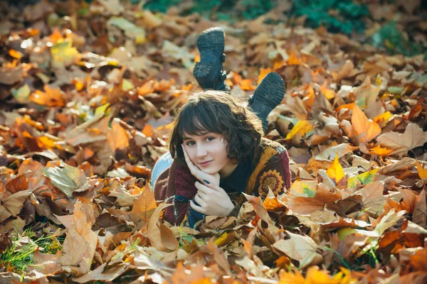 Herfst vrouw liggend over bladeren en lachend. Portret van een meisje. Meisje in de herfst oranje bladeren. Warm zonnig weer. Seizoensgebonden. Jonge vrouw geniet van herfstweer. — Stockfoto