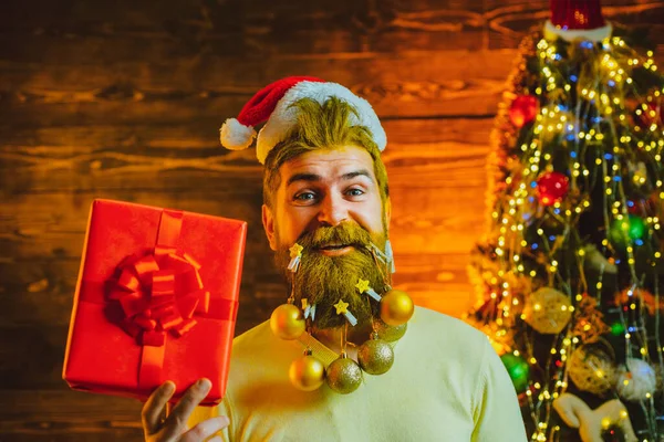 Regalos de entrega. Año Nuevo, tarjeta de Navidad. Hipster Papá Noel moderno desea Feliz Navidad. Estilo Santa Claus con una larga barba posando sobre el fondo de madera. —  Fotos de Stock