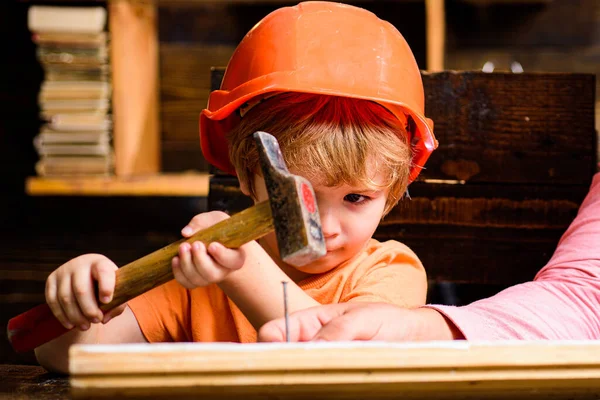 Funny little repairman with hammer. Kids construction worker. Child use a hammer to nail.