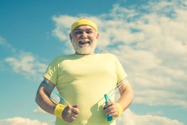 En iyi kardiyo egzersizi. Son sınıf öğrencisi fitness eğitimi alıyor. Büyükbaba sporcu mavi gökyüzü arka planında.