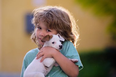 Yavru köpekle oynayan çocuğun portresi. Yazın çocuklar ve beyaz köpek yavrusu.