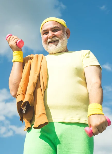 Rehabilitation center for elderly aged pensioner. Senior sport man lifting dumbbells in sport center.