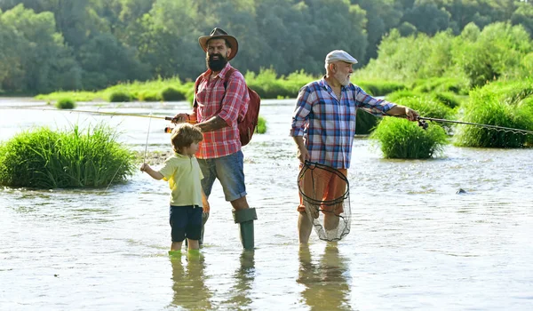 Людина в різний вік. Риболовля. Дідусь і онук летять на риболовлю на річці. Чоловік навчає дітей рибалити в річці . — стокове фото
