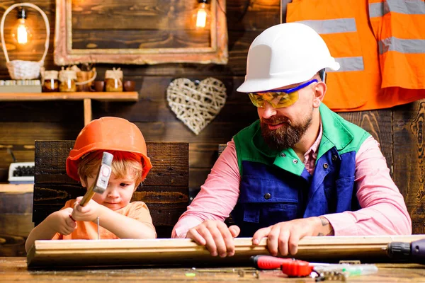 Vader en zoon hameren nagels met een hamer in een houten plank. Gelukkig vaderschap. — Stockfoto