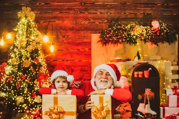 Aile tatili. Küçük Noel Baba ve torunu torbasıyla birlikte Noel hediyesini getirdi. Yetenekli Noel Baba yardımcısı. Noel Baba torun yardımcısı.