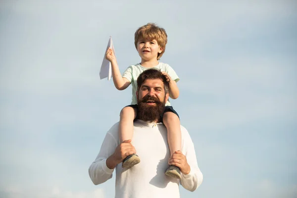 Día de los Padres. Papá e hijo jugando juntos. Retrato de padre feliz dando hijo paseo a cuestas sobre sus hombros y mirando hacia arriba. — Foto de Stock