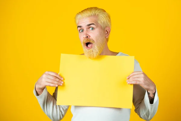 Человек держит чистый лист бумаги, изолированный на желтом фоне. — стоковое фото