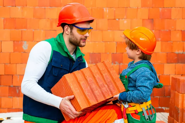 Little boy bricklayer. Brothers are building together. Brbuilder work with brick layer