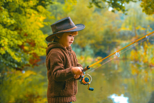Child fishing at autumn lake. Kid with fishingrod.