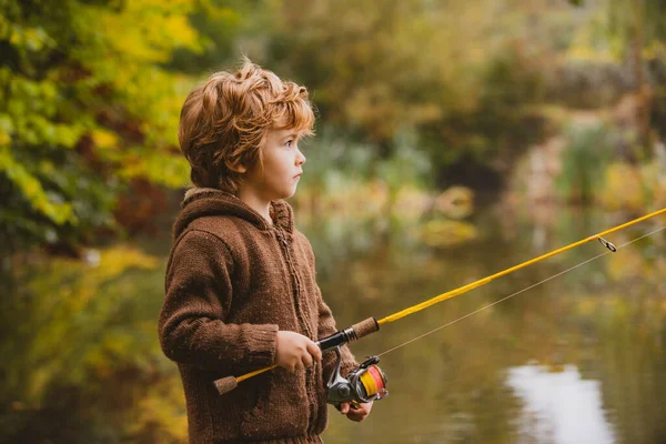 Porträtt av glada lilla barn son fiske på floden med snurrande rulle. Glada barn höst helg koncept. — Stockfoto