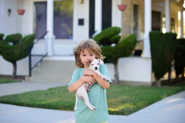 Filhote de cachorro nas mãos dos miúdos. Criança feliz brincando com o cão no jardim . — Fotografia de Stock