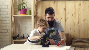 Kafkasyalı baba ve anaokulu çocuğu birlikte dinozor figürleriyle oynuyorlar. Oyuncu baba ve küçük çocuk evde iyi eğlenceler. Bebekler için eğitici oyuncaklar.