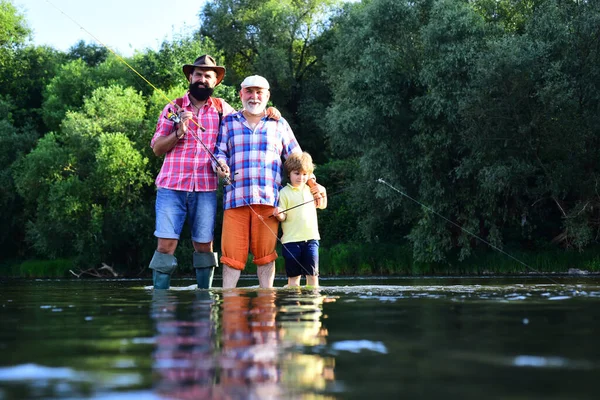 Ragazzo con padre e nonno pesca a mosca all'aperto sullo sfondo del fiume. Pesca. Padre, figlio e nonno in battuta di pesca. Pesca nel fiume. — Foto Stock